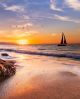 A Sailboat Sails Along The Ocean At Sunset Canvas Print